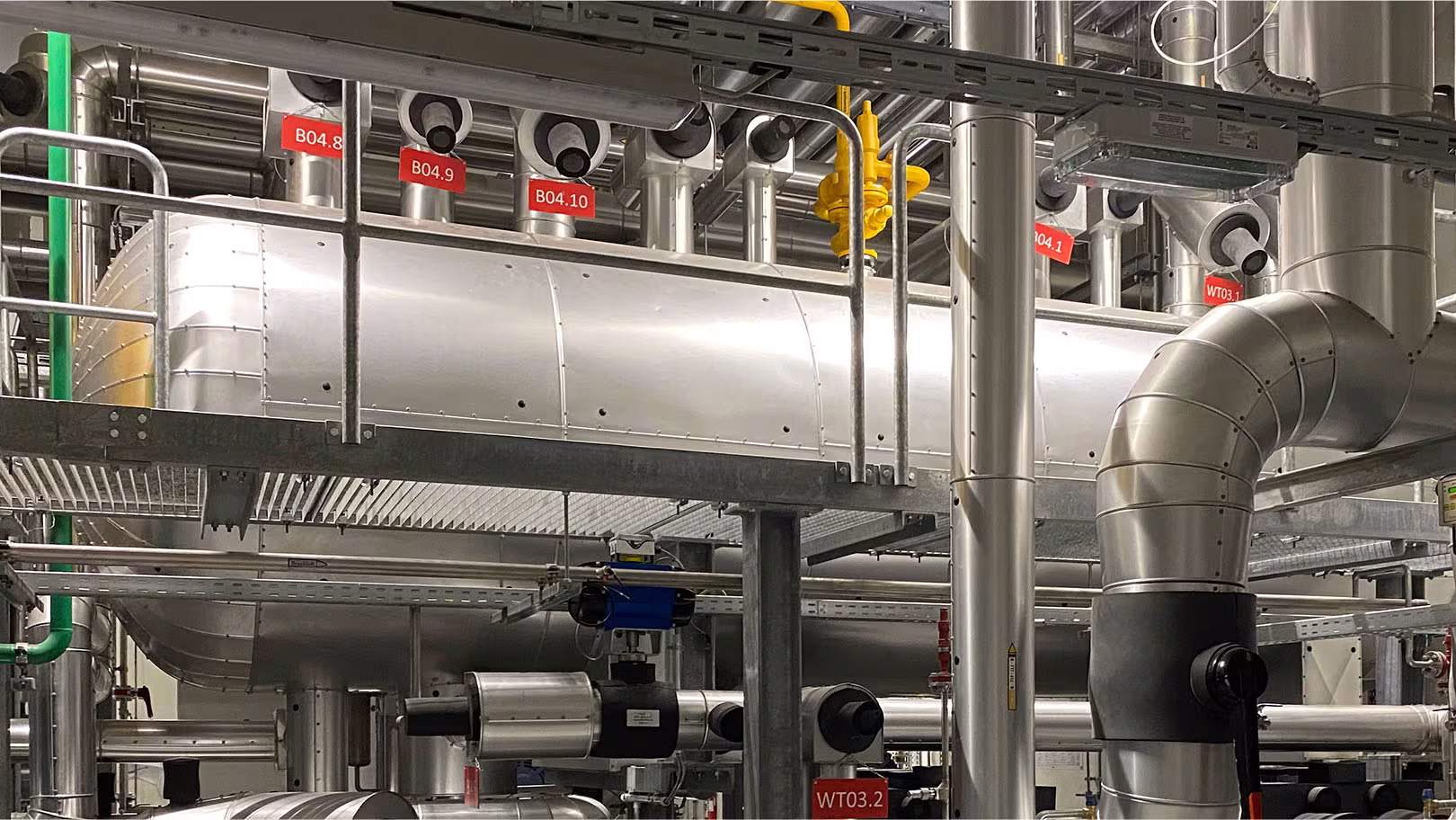 Komplett isolierter Maschinenraum mit beschrifteten Rohrleitungen B04 und Wärmetauschern WT03 – Skid-Montage durch IVS